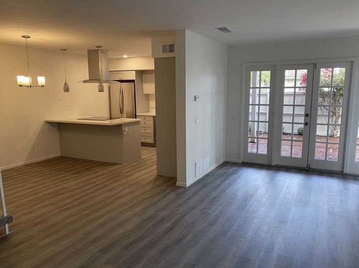 Open-plan kitchen and living room with new flooring, pendant lights and French doors