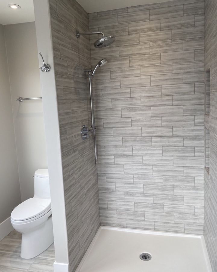 Walk-in shower with offset gray tile, rain head and slide-bar hand shower